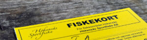 Gul fiskekort från Hökensås Sportfiske ligger på en träytan.
